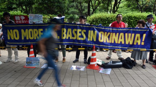 Protesters hold a banner which reads as "No More US Bases in Okinawa" as they attend a rally against a security bill outside the Diet building in Tokyo on June 14, 2015. Almost 25,000 protesters gathered around the Diet building to oppose a controversial bill for Japan's growing security engagement.         AFP PHOTO / TOSHIFUMI KITAMURA        (Photo credit should read TOSHIFUMI KITAMURA/AFP/Getty Images)